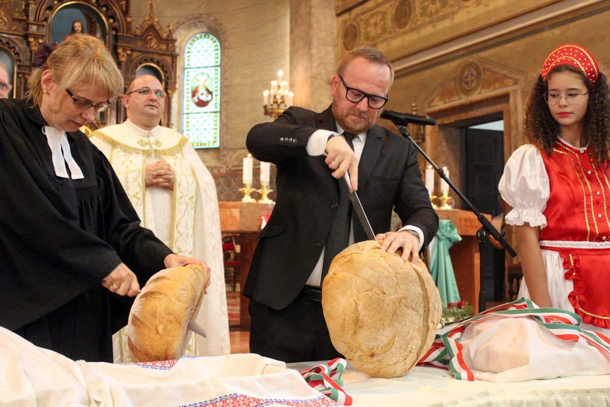 Szabó Péter leköszönő paksi polgármester szeli a kenyeret a Jézus Szíve római katolikus nagytemplomban augusztus huszadikán 